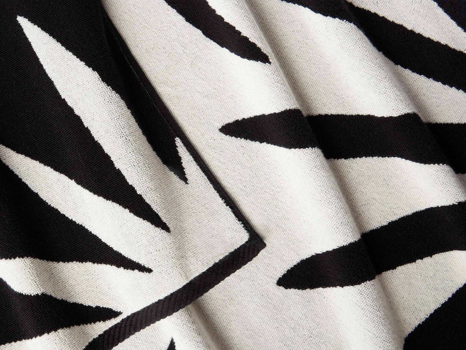 
      A close-up of a thick and soft, black and white tropical patterned cabana beach towel.
    