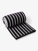A rolled-up, black and white striped cabana beach towel. 
