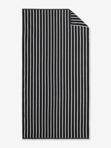 An oversized black and white striped cabana beach towel laid out.