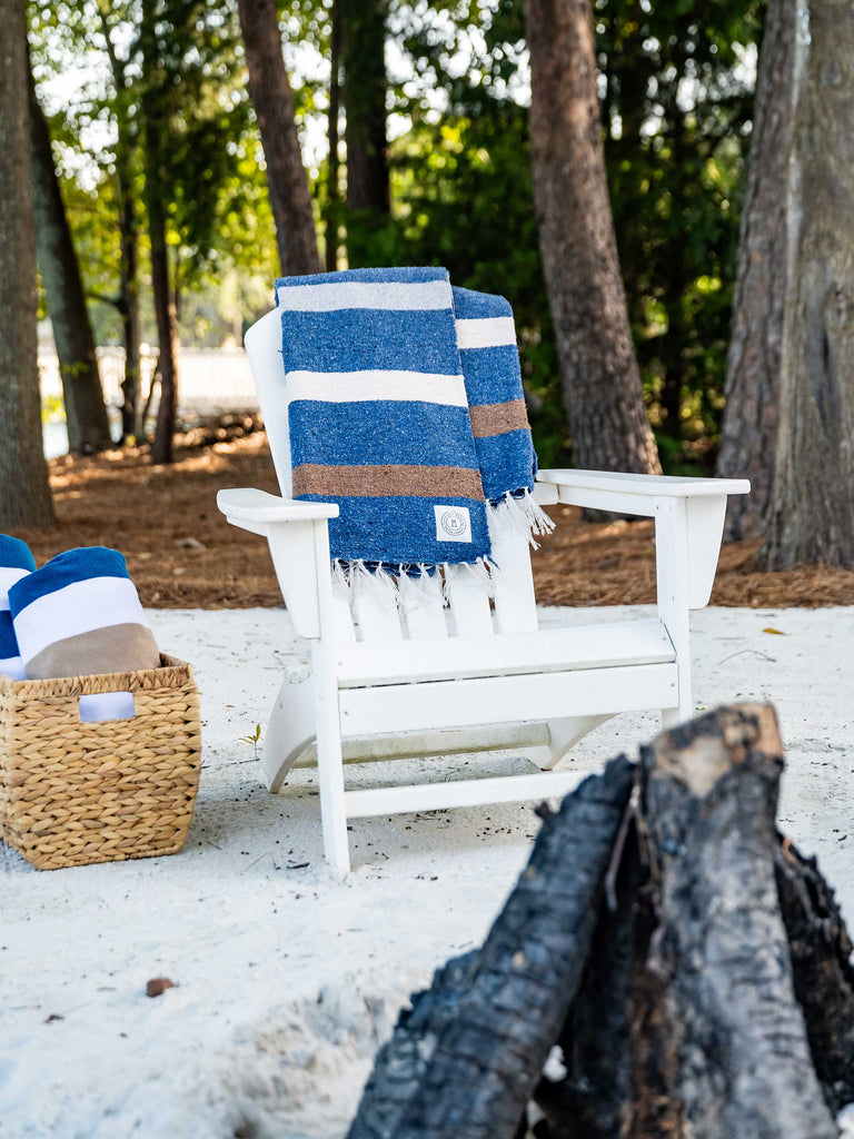 A navy blue striped Mexican Blanket draped over a white chair outside.