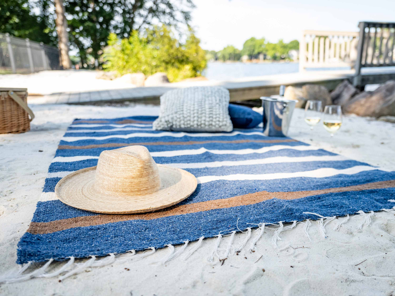
      A navy, brown, and white striped Mexican Blanket laid out on the sand.
    