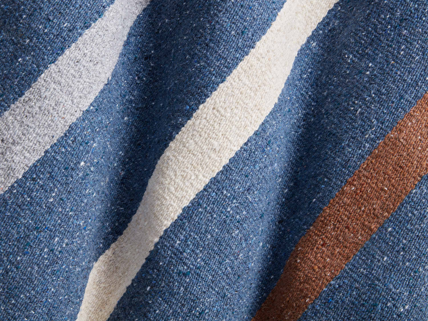 
      A close up shot of brown and white stripes on a navy Mexican Blanket.
    