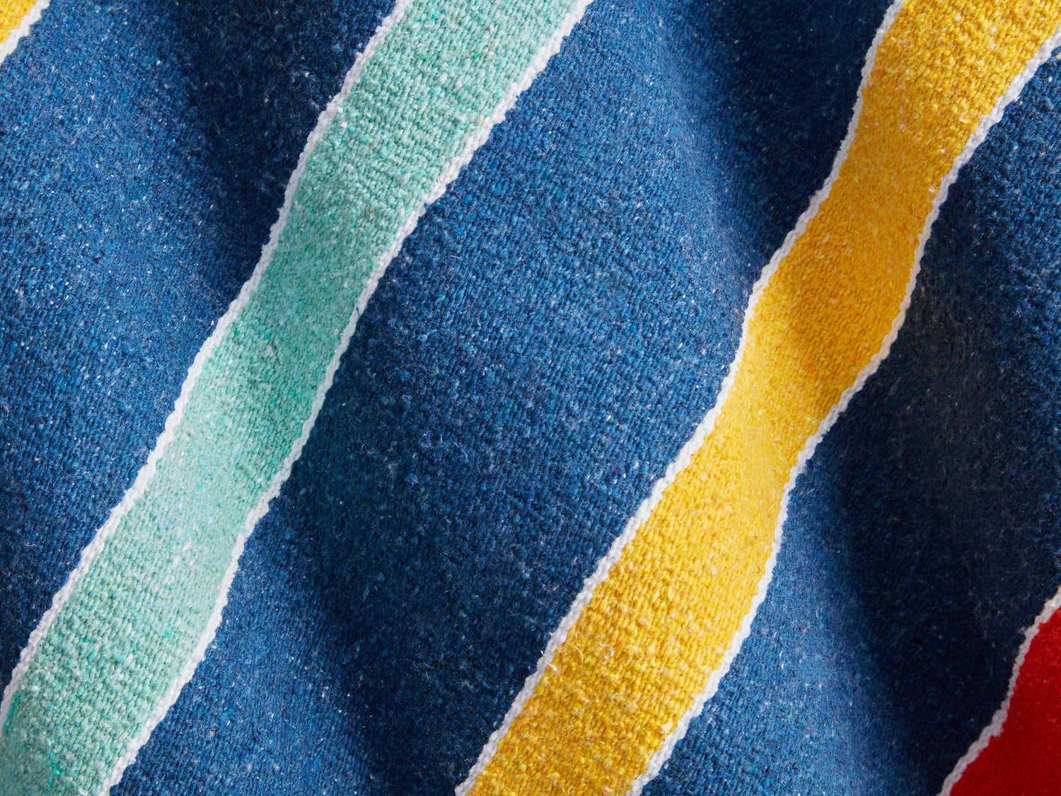 
      A close up shot of blue and yellow stripes on a Mexican Blanket.
    
