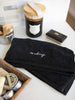 Two soft black makeup towels with embroidery in modern bathroom.