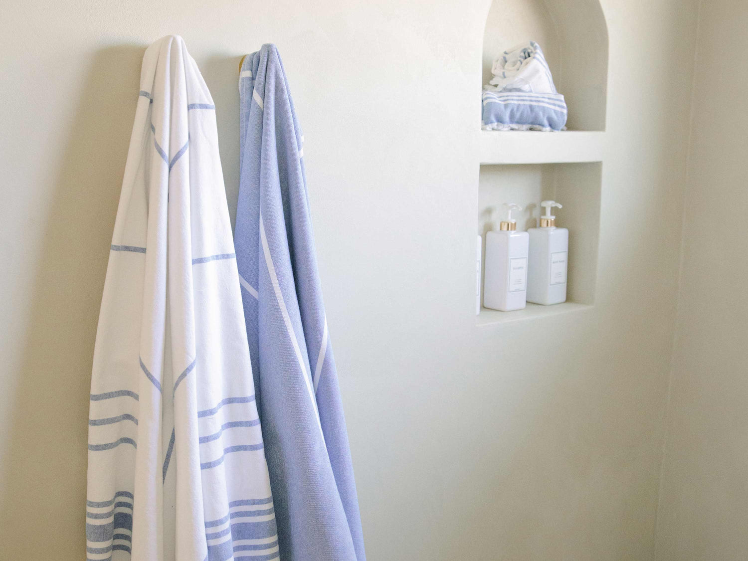 
      White and blue striped oversized Turkish towels in a modern bathroom.
    