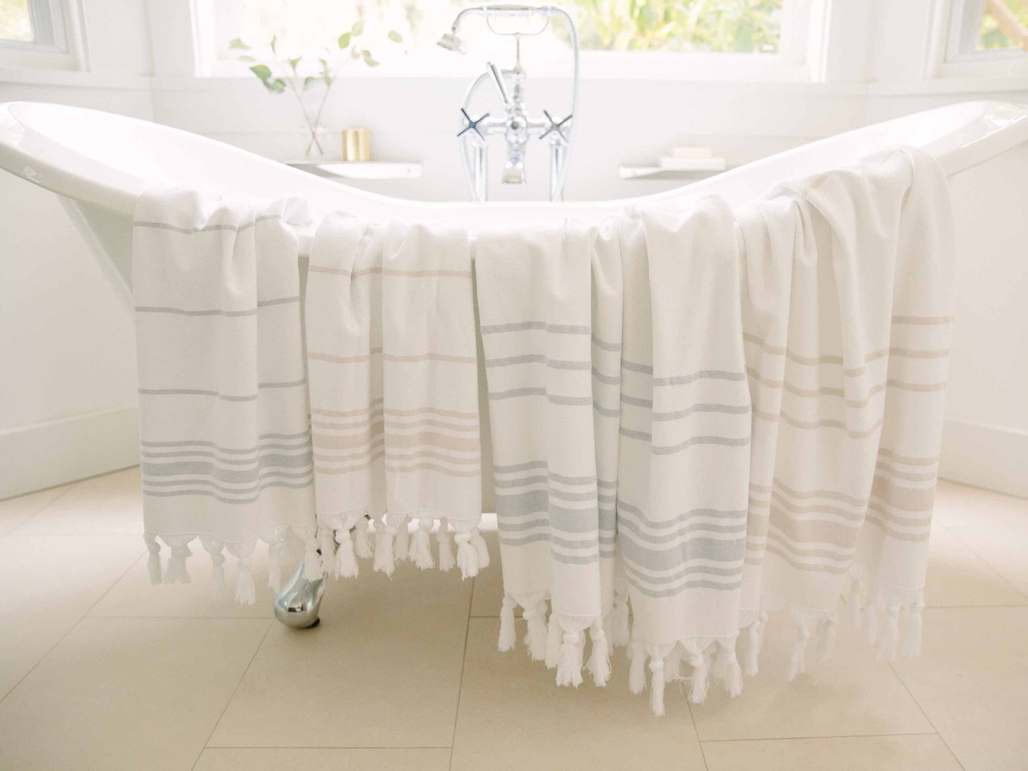 
      White, gray, and tan Turkish towel draped over classic bathtub.
    