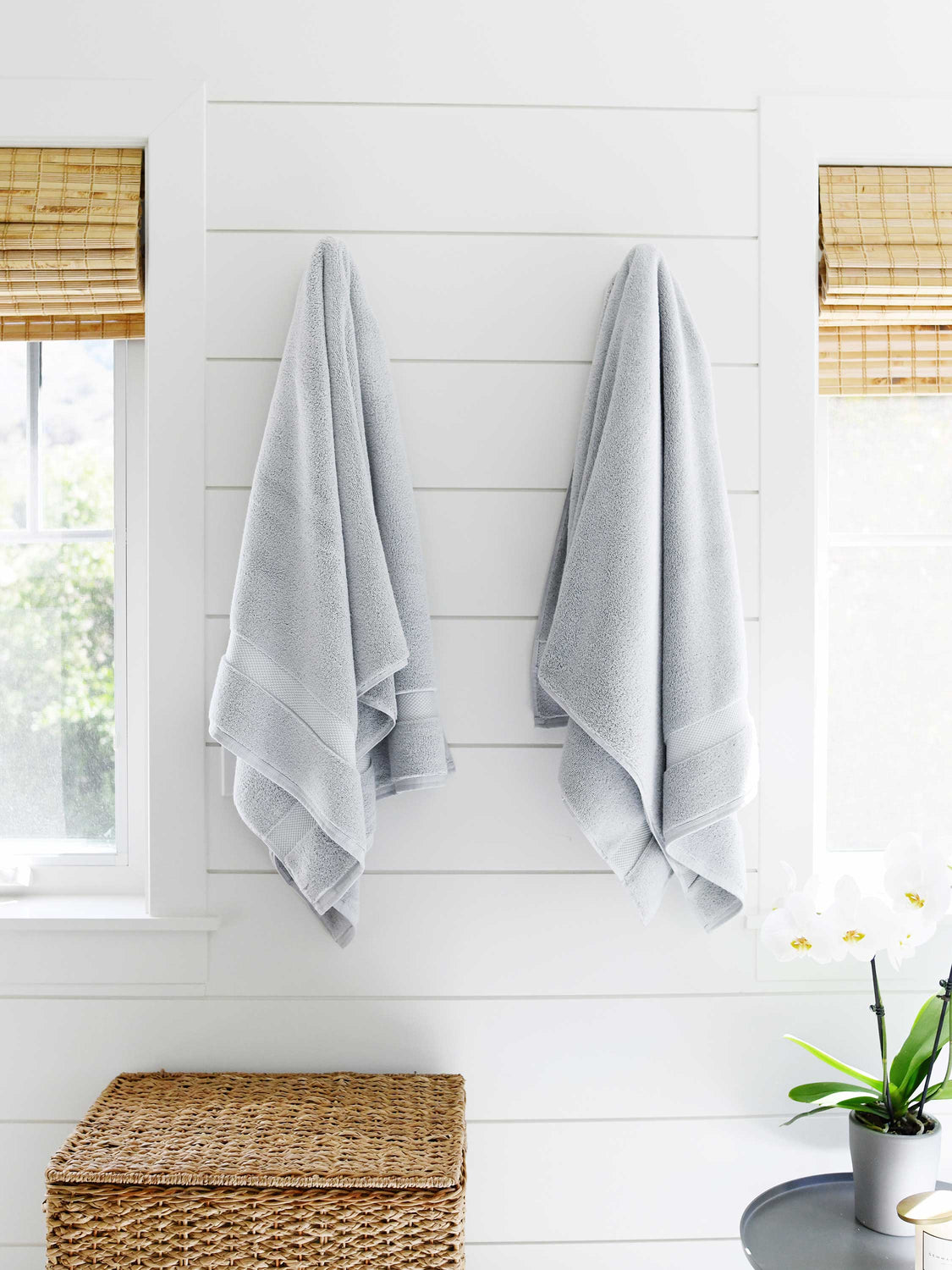 A pair of cloud gray supima cotton bath towels hanging on the a side by side.