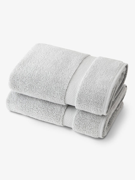 A pair of cloud gray supine cotton bath towels folded over one another.