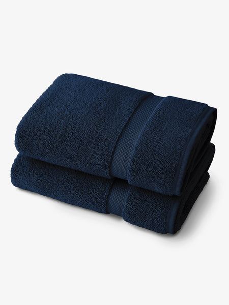 A pair of navy blue cotton bath towels folded on one another.