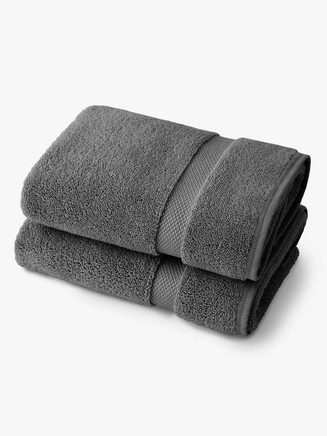 A pair of dark gray cotton bath towels folded on top of one another.