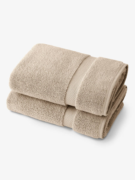 A pair of tan cotton bath towels folded over one another.