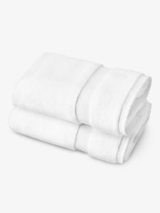 A pair of white cotton bath towels folded over one another.