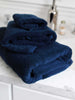 A set of blue cotton bath towels folded and stacked on one another on top of a counter.