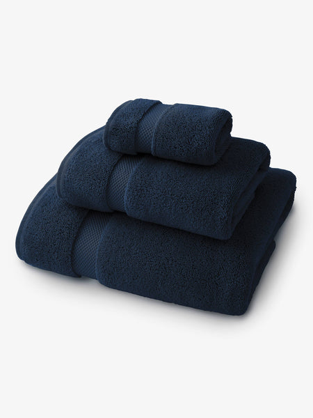 A set of navy blue bath, hand, and wash towels folded and stacked on one another.