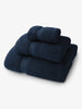 A set of navy blue bath, hand, and wash towels folded and stacked on one another.