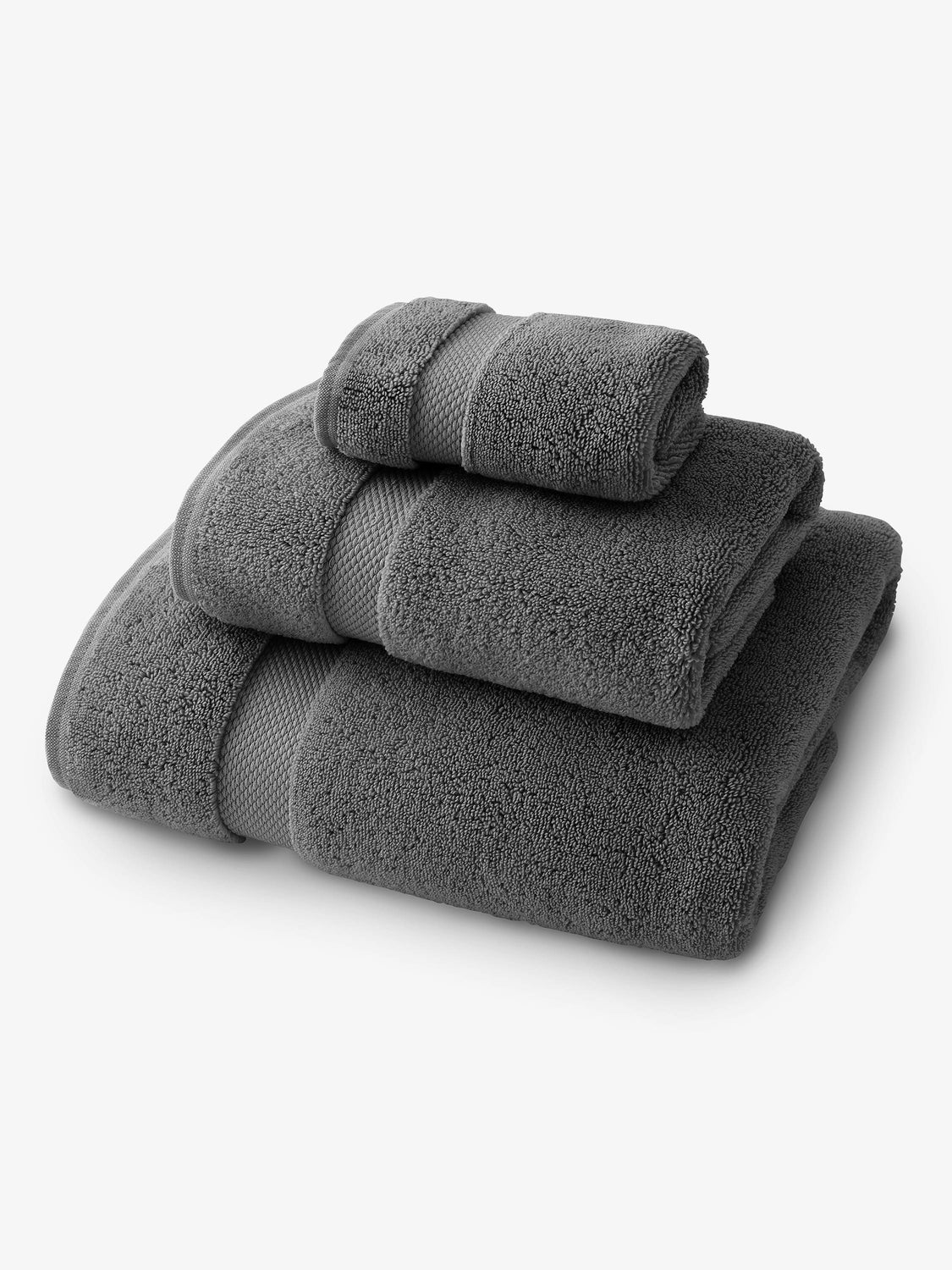A set of dark gray bath, hand, and wash towels folded and stacked on one another.