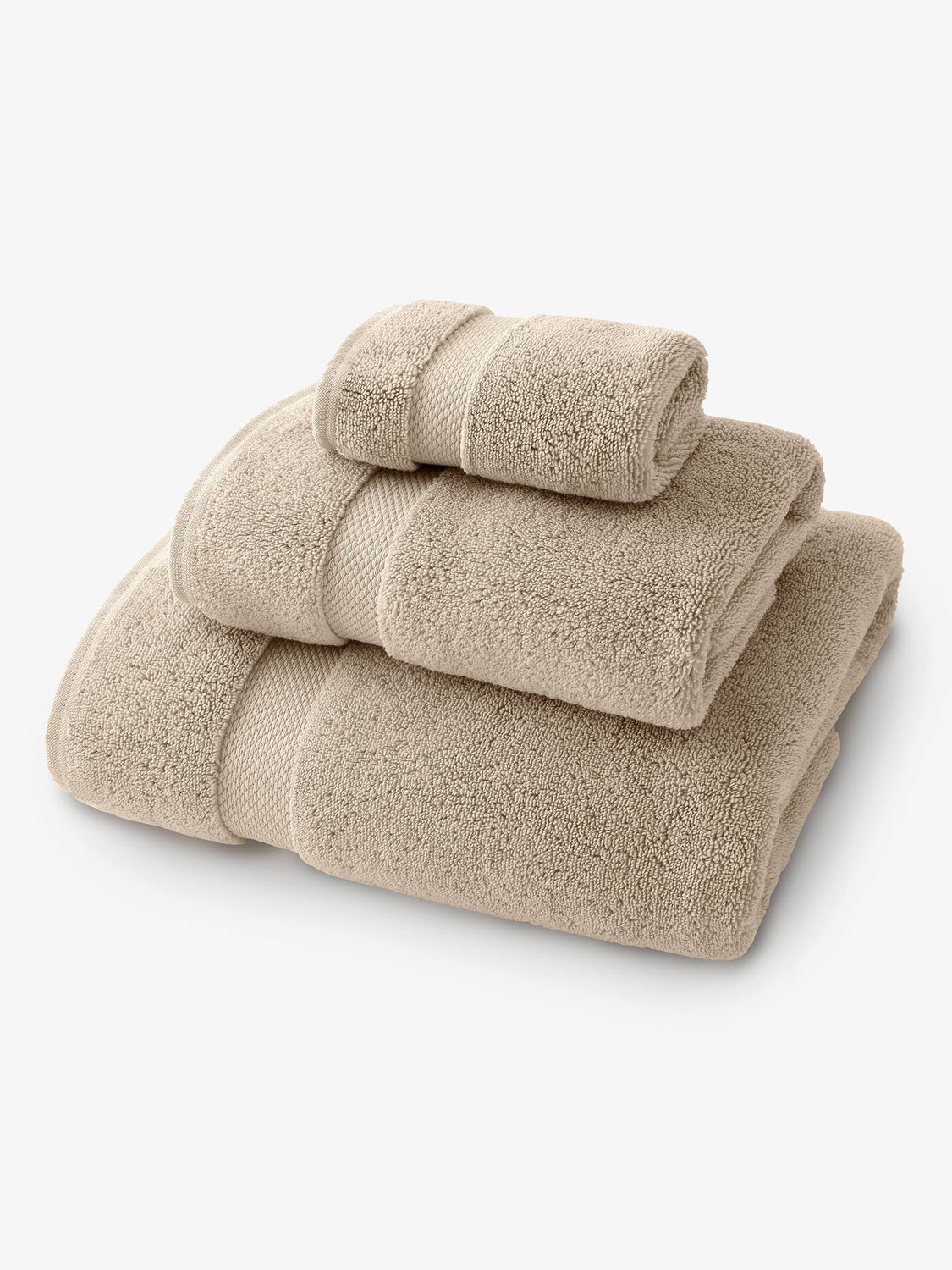 A set of tan bath, hand, and wash towels folded and stacked on one another.
