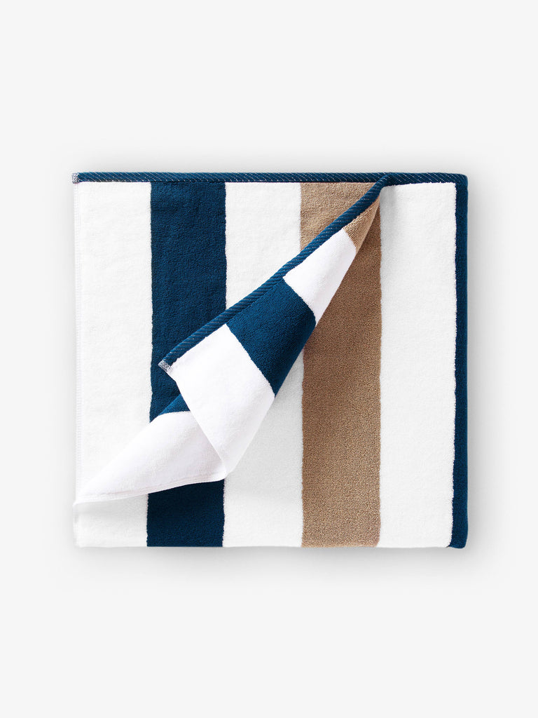A folded blue, brown, and white striped cabana beach towel.