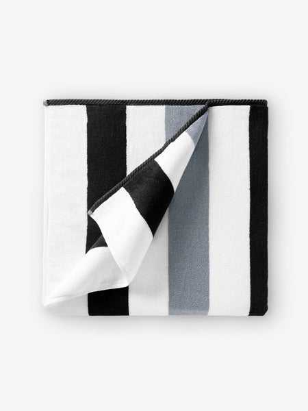 A folded black, gray, and white striped cabana beach towel.
