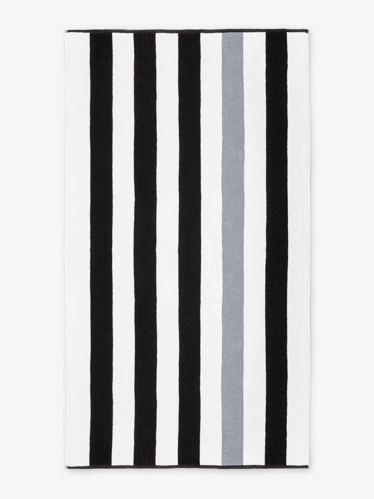 An oversized, black, gray, and white striped cabana beach towel laid out.
