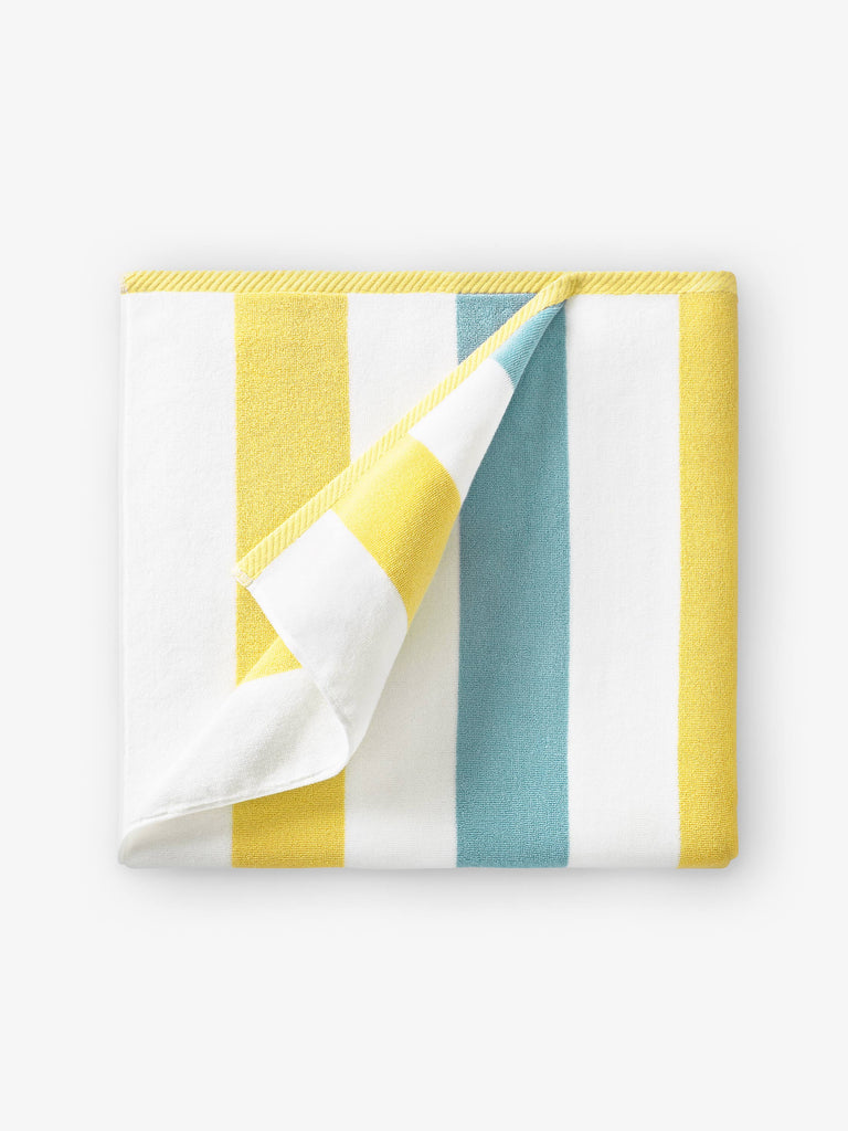 A folded yellow, green, and white striped cabana beach towel.