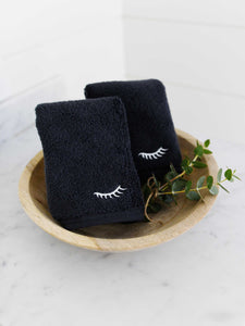 A pair of black makeup towels folded in a decorative bowl.