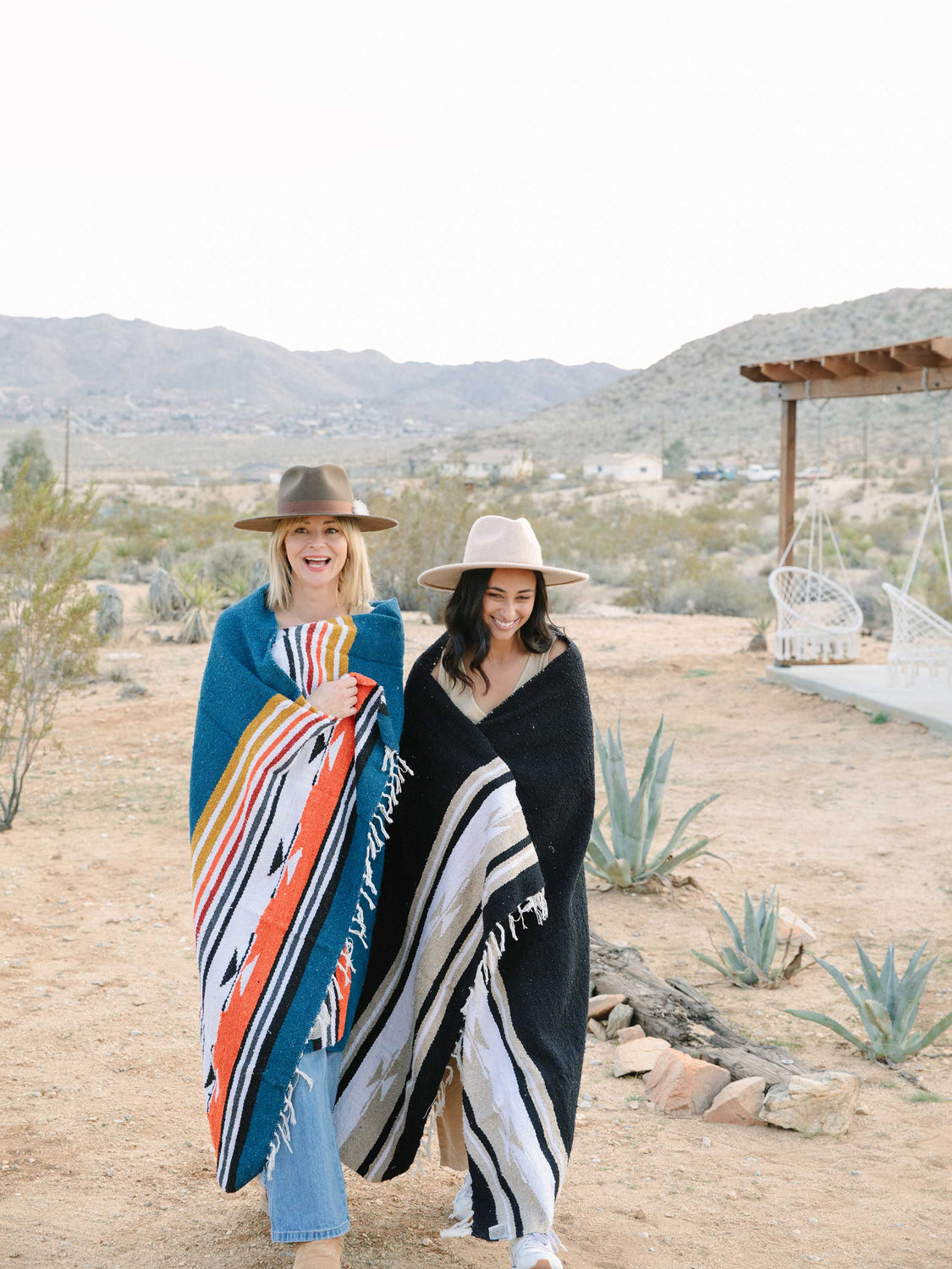 Two woman walking in California desert wrapped in blue and black Mexican blankets.