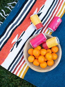 Close-up of a navy blue, red, and yellow Mexican blanket laid out on the grass for an outdoor picnic. 