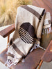 Close-up of a large, brown Mexican blanket draped over an outdoor metal chair.