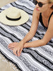 Close-up of a woman sunbathing at the beach on an oversized black, white, and gray traditional Mexican blanket.