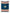 Oversized, traditional Mexican blanket in navy blue, red, and yellow pattern with white fringe spread out. 