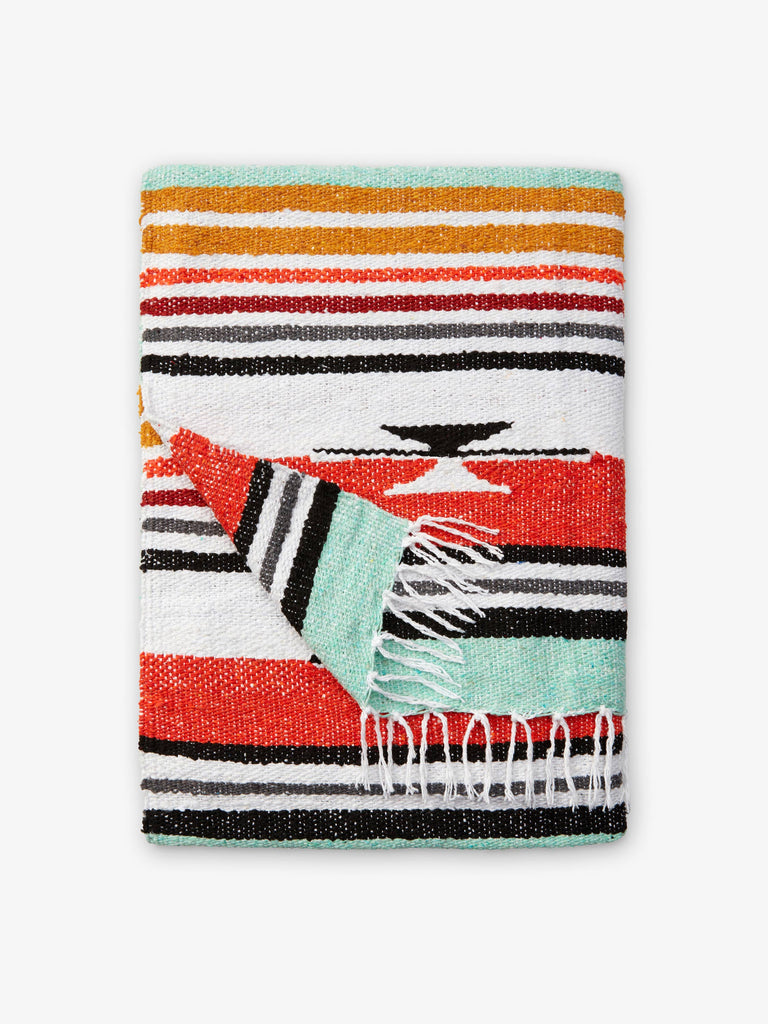 A folded traditional, hand-woven Mexican blanket in green, red, and yellow pattern with fringe.