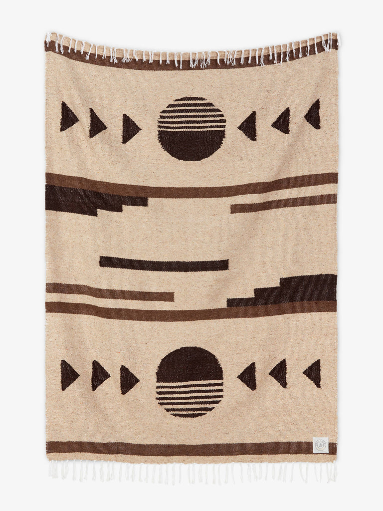 Oversized, traditional Mexican blanket in tan, brown, and black design with white fringe spread out.