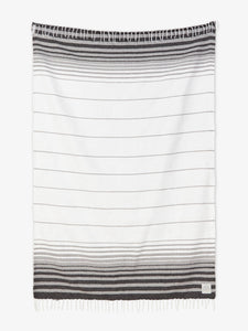 Oversized, traditional Mexican blanket in gray and white stripe design with white fringe spread out.