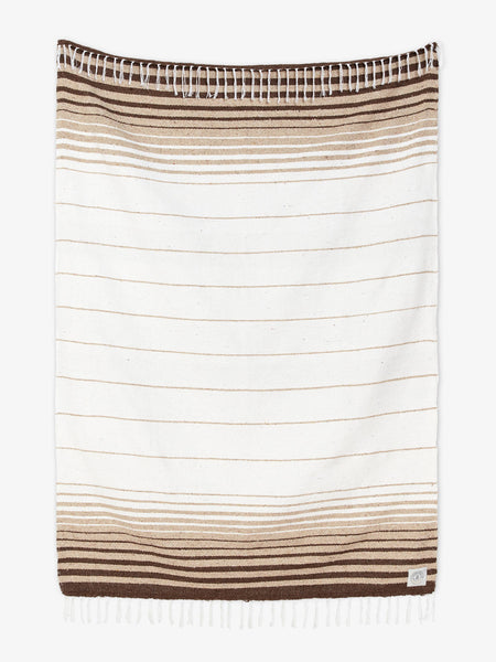 Oversized, traditional Mexican blanket in brown, tan, and white stripe pattern with white fringe spread out.