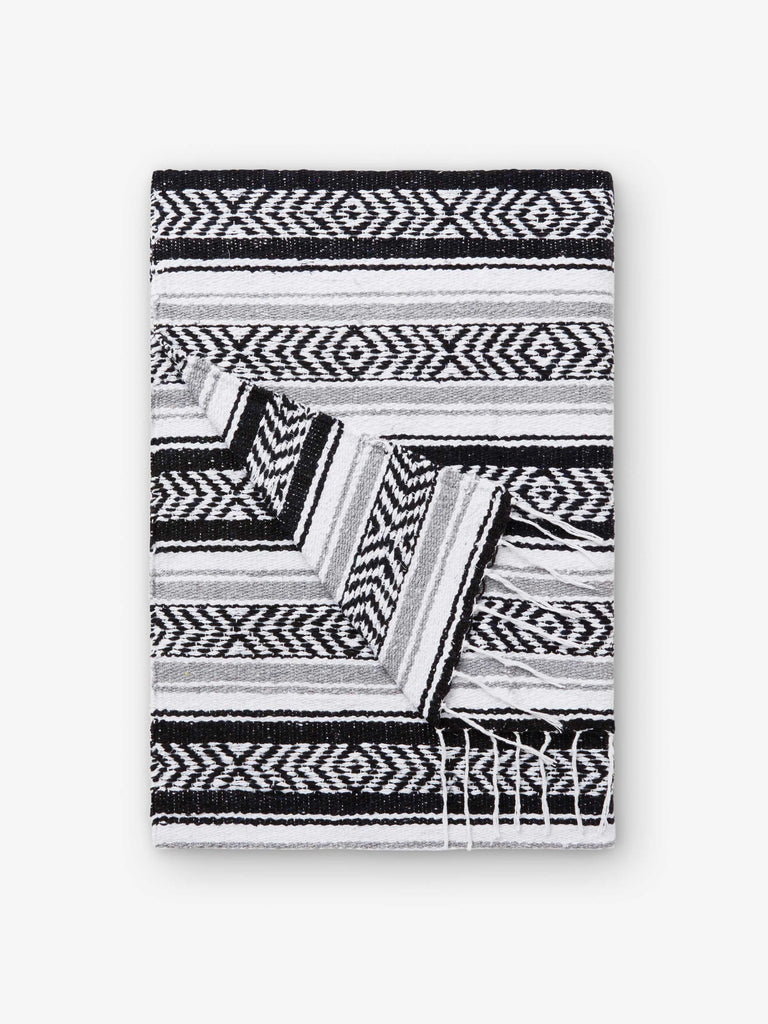 A folded traditional, hand-woven Mexican blanket in black, gray, and white.