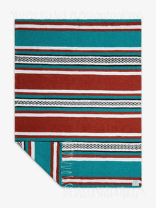 Oversized, traditional Mexican blanket in green, red, and white striped pattern with white fringe spread out. 