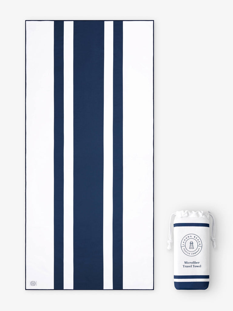 An oversized, quick drying navy blue and white striped microfiber beach towel laid out next to a matching travel bag.