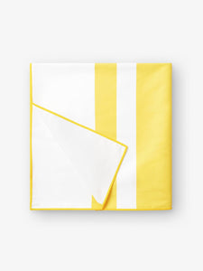 A folded quick drying, yellow and white striped microfiber beach towel.