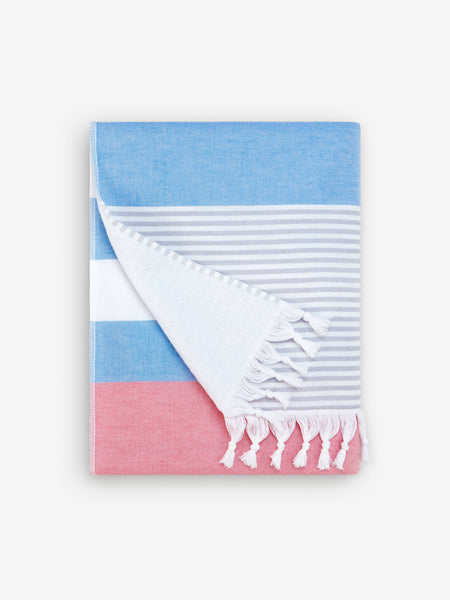 A folded blue, pink, and white striped Turkish towel with white fringe.