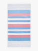 An oversized, blue, pink, and white striped Turkish cotton towel with white fringe laid out.