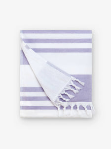 A folded white and purple striped Turkish towel with white fringe.