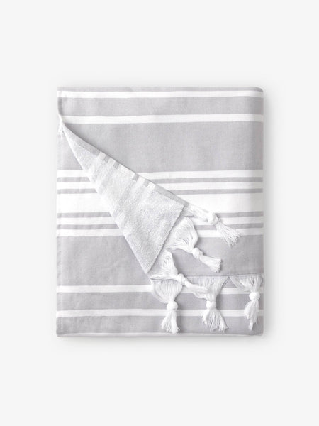 A folded gray and white striped Turkish towel with white fringe.