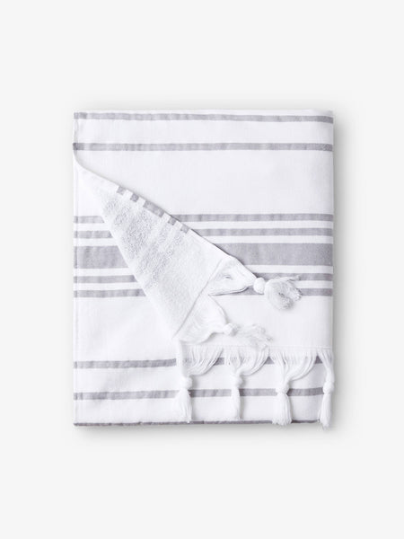 A folded white and gray striped Turkish towel with white fringe.