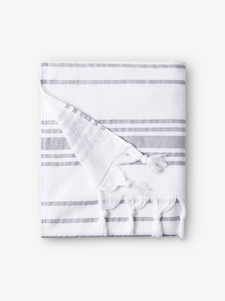 A folded white and gray striped Turkish towel with white fringe.