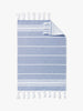 An authentic blue and white Turkish hand towel with fringe laid out.