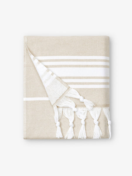 A folded white and tan striped Turkish towel with white fringe. 
