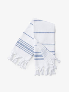A folded blue and white striped Turkish hand towel with white fringe.