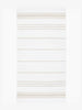 An oversized tan and white striped Turkish cotton towel with white fringe laid out. 