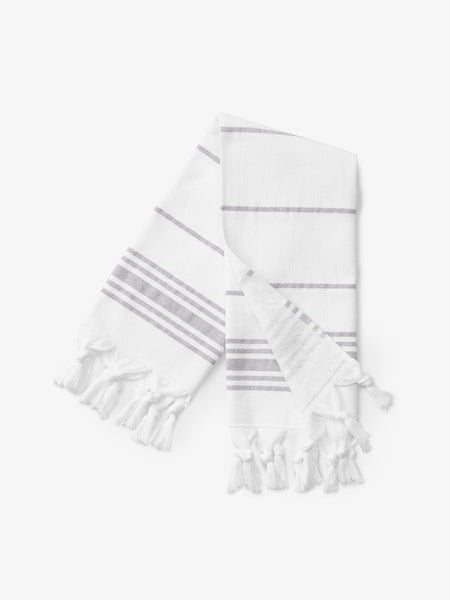 A folded gray and white striped Turkish hand towel with white fringe.
